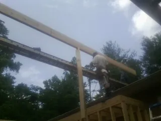 Carpenter setting a ridge beam over a new addition frame — Ice Dam Removal by Roofing Brothers in Fentress