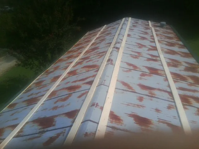 Rusted metal roof panels with new wood purlins before replacement — Storm Damage Roof Repair in Fentress by Roofing Brothers
