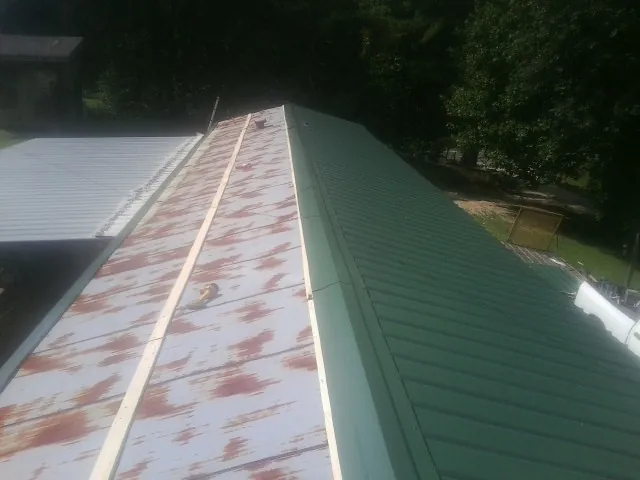 Old rusted panels beside newly installed green metal roofing — Wind Damage Roof Repair by Roofing Brothers in Fentress
