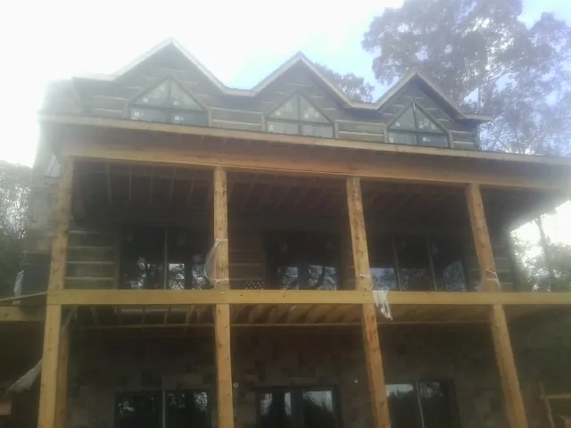 Dormers and porch framing on a large log home under construction — Roof Coating work by our crew in Fentress