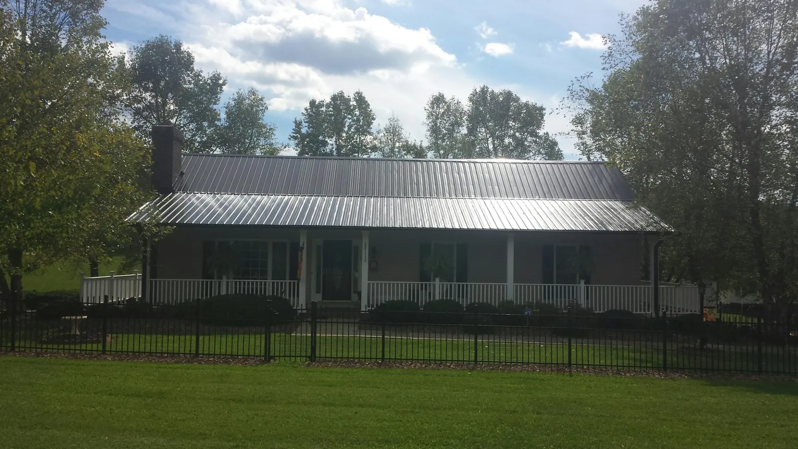 Gray metal roof on a brick ranch with a full width front porch — Gutter Guard Installation work by our crew in Fentress