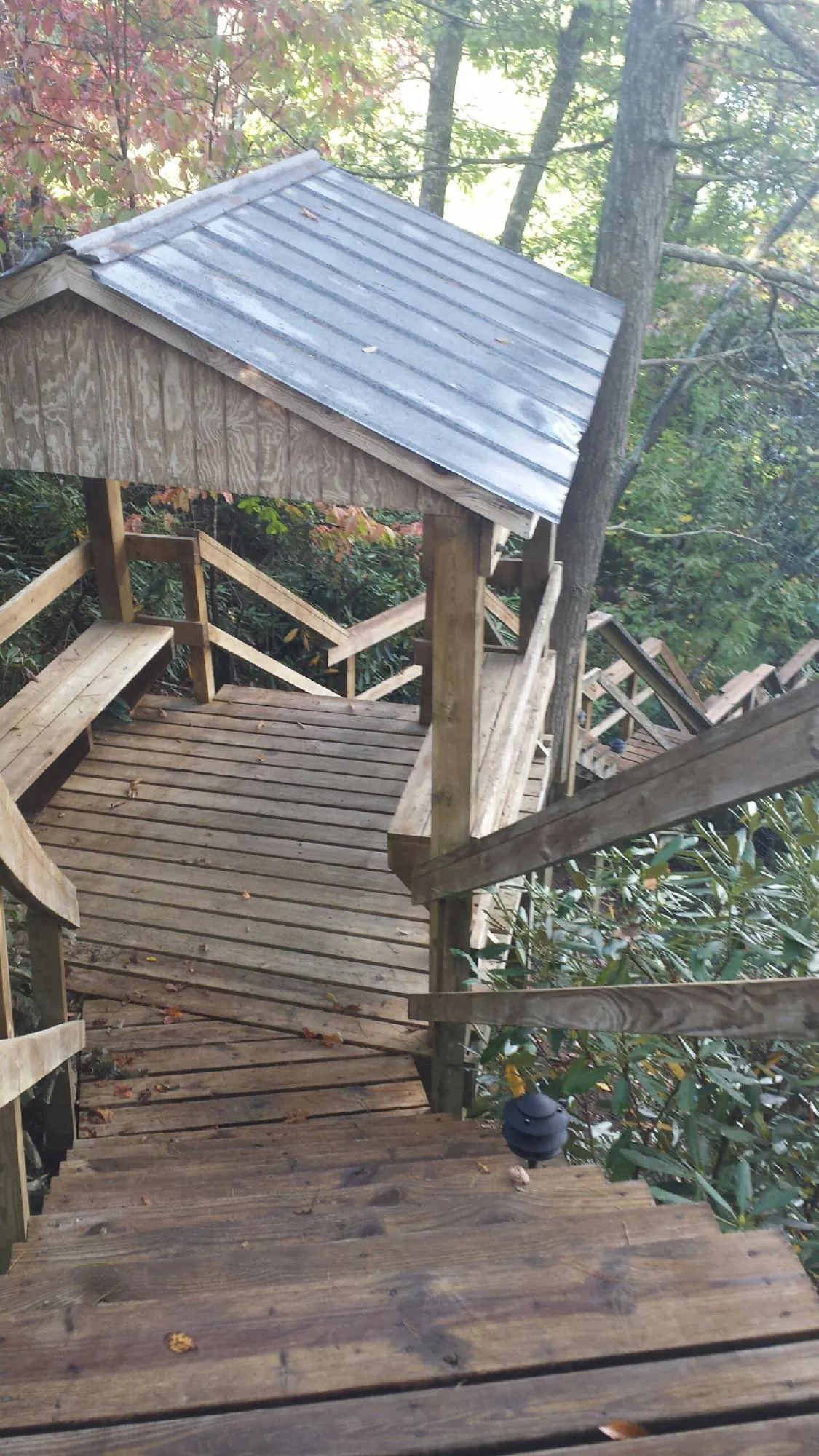 Metal roofed shelter over wooden steps on a wooded walkway — Skylight Repair & Installation work by our crew in Fentress