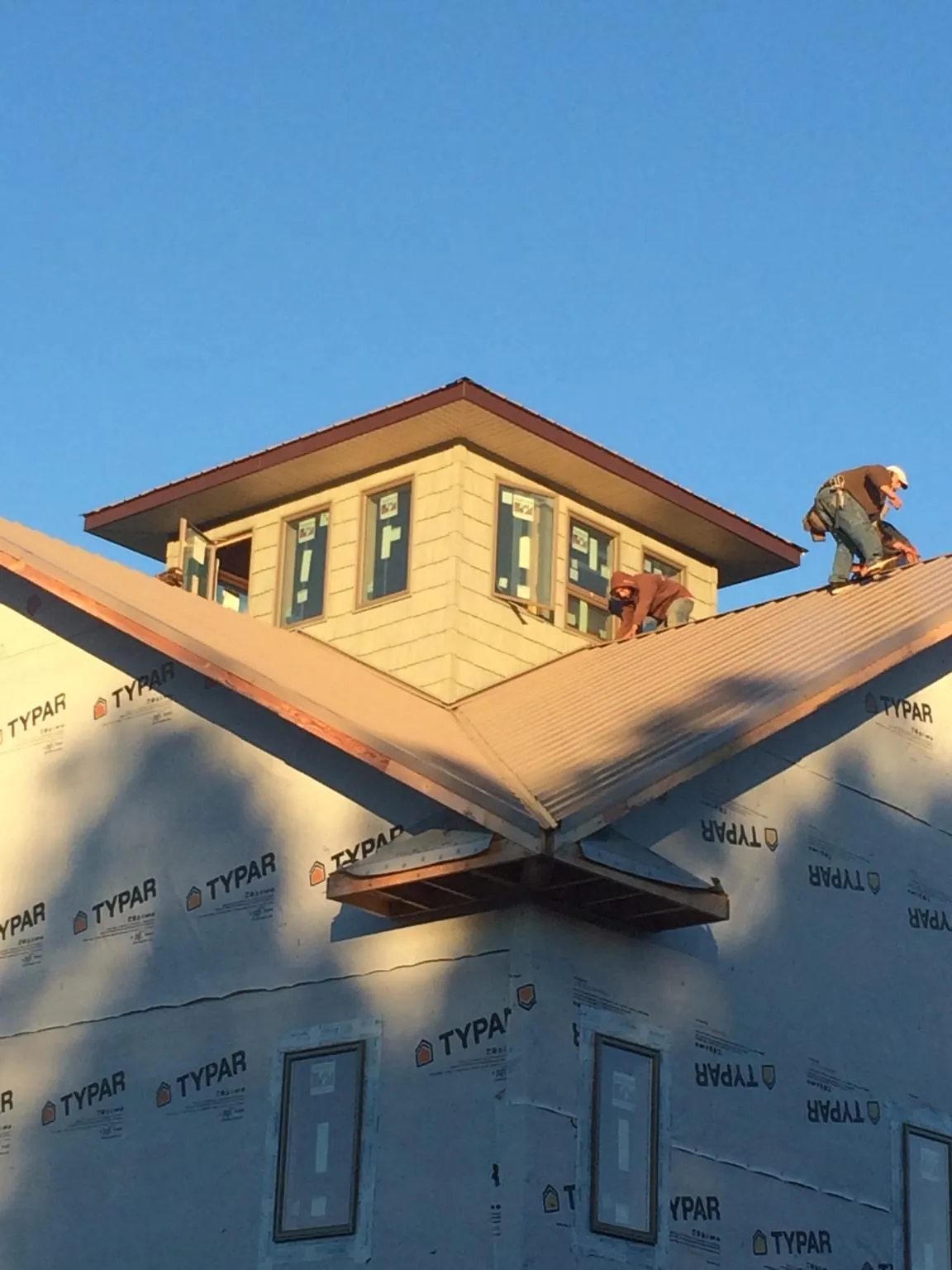 Roofers working around a rooftop cupola on a new metal roof at sunset — Roof Waterproofing in Fentress by Roofing Brothers
